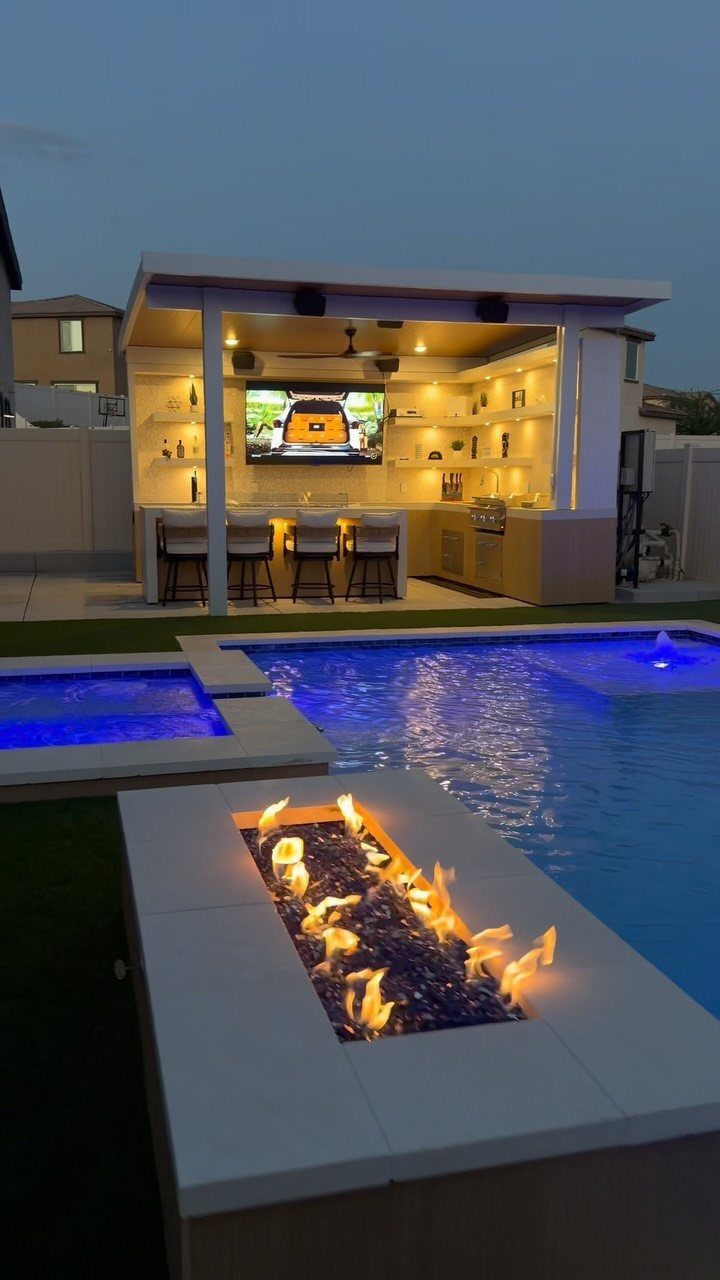 An outdoor patio bar with a television and stools next to a blue swimming pool.