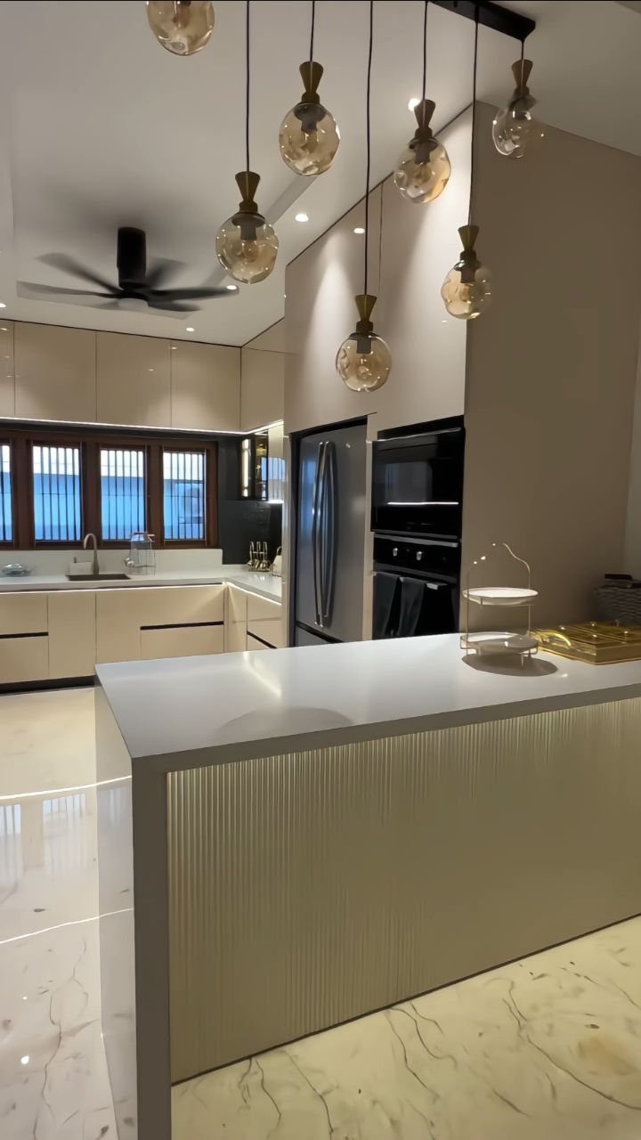 Modern kitchen with beige cabinets, white countertops, and hanging glass globe pendant lights.