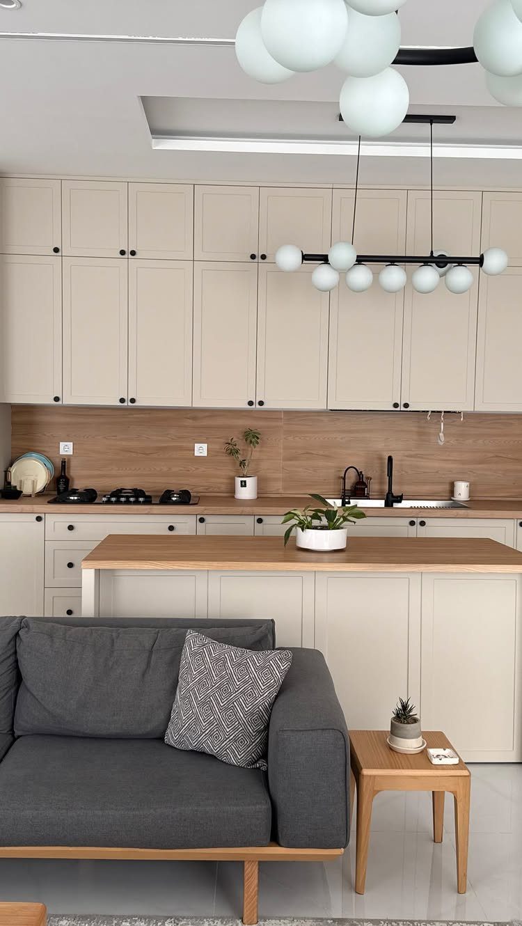 Beige kitchen cabinets paired with a wood grain backsplash and a wooden kitchen island countertop.