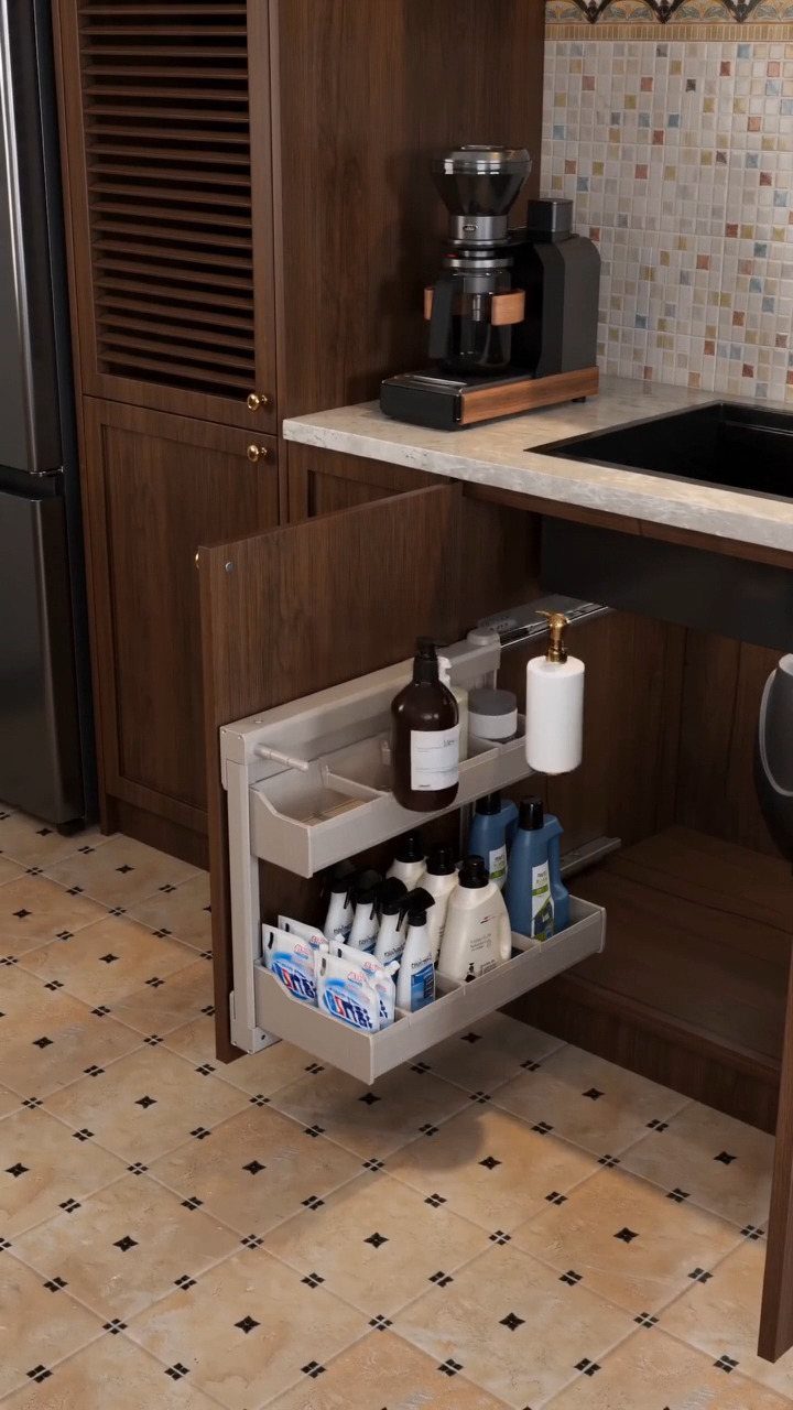 A pull-out organizer under a kitchen sink filled with various cleaning supply bottles.