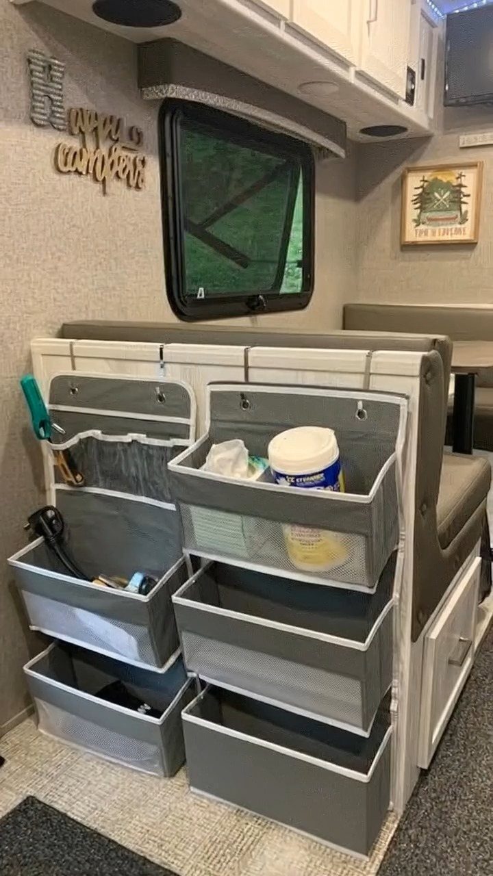 Grey fabric hanging organizer pockets filled with supplies mounted on the back of a camper seat.