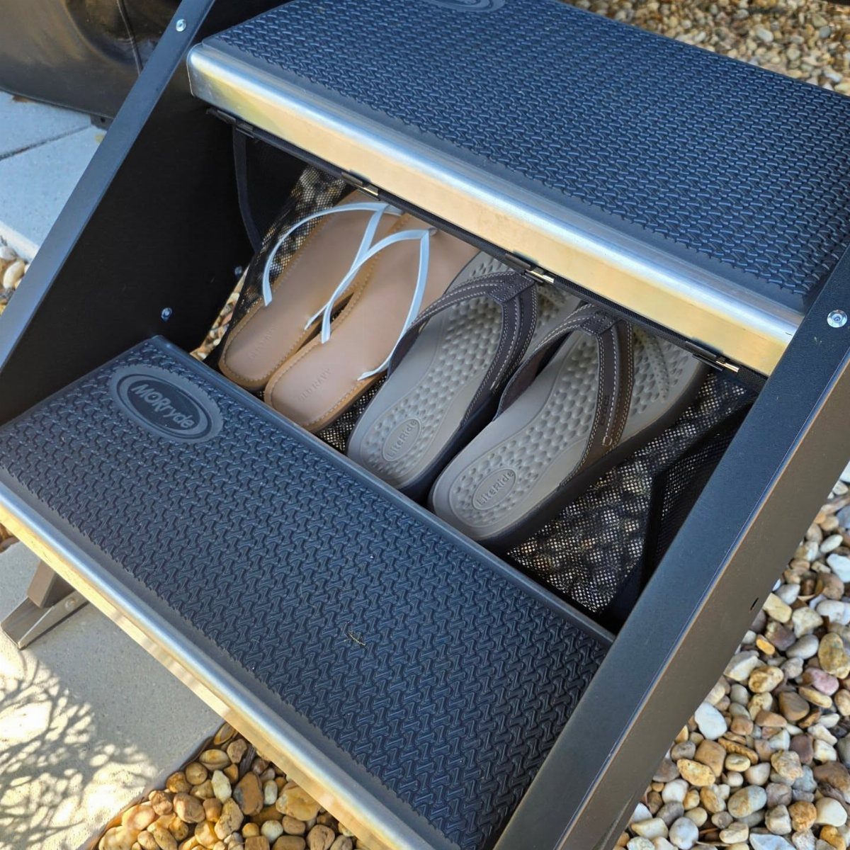 Two pairs of flip-flops stored inside a compartment under a black step stool.