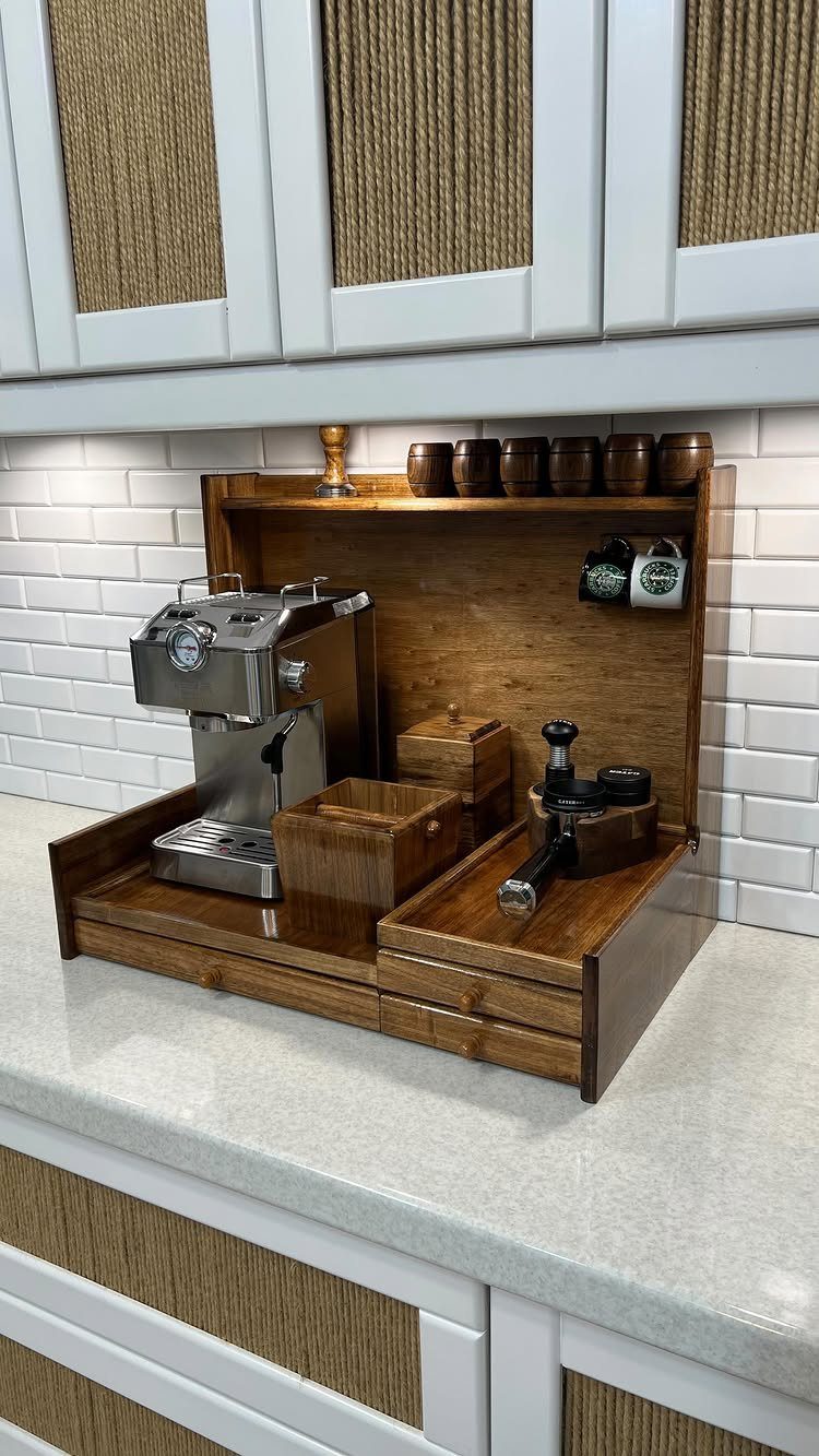 A wooden espresso station with a silver machine on a white kitchen countertop.