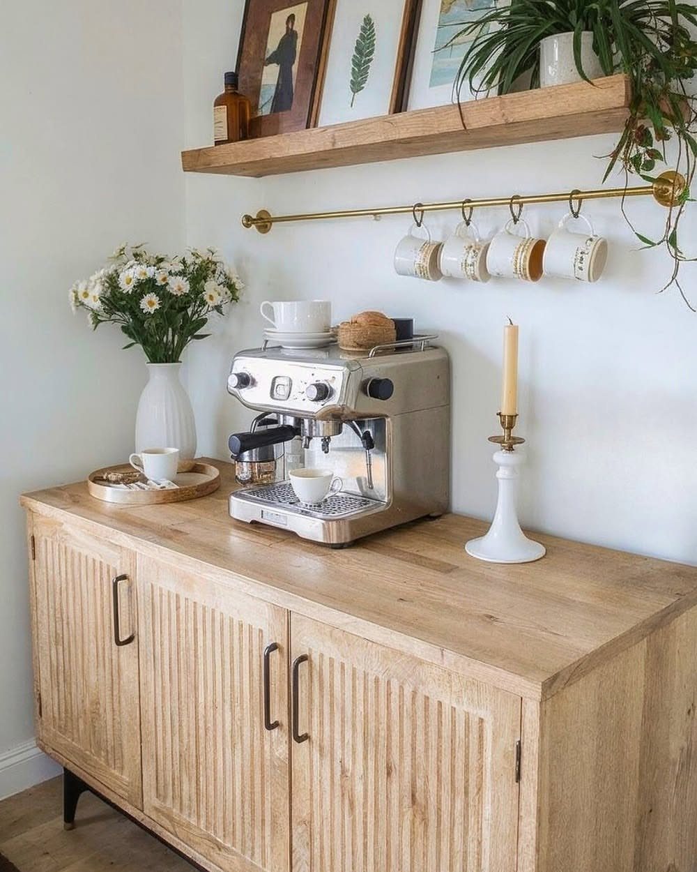 A wooden coffee station featuring an espresso machine on a cabinet with a floating shelf above.