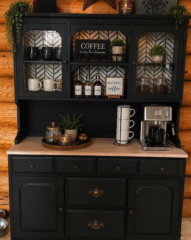 Black kitchen hutch coffee bar with espresso machine, mugs, and decorative coffee signage on a wooden counter.