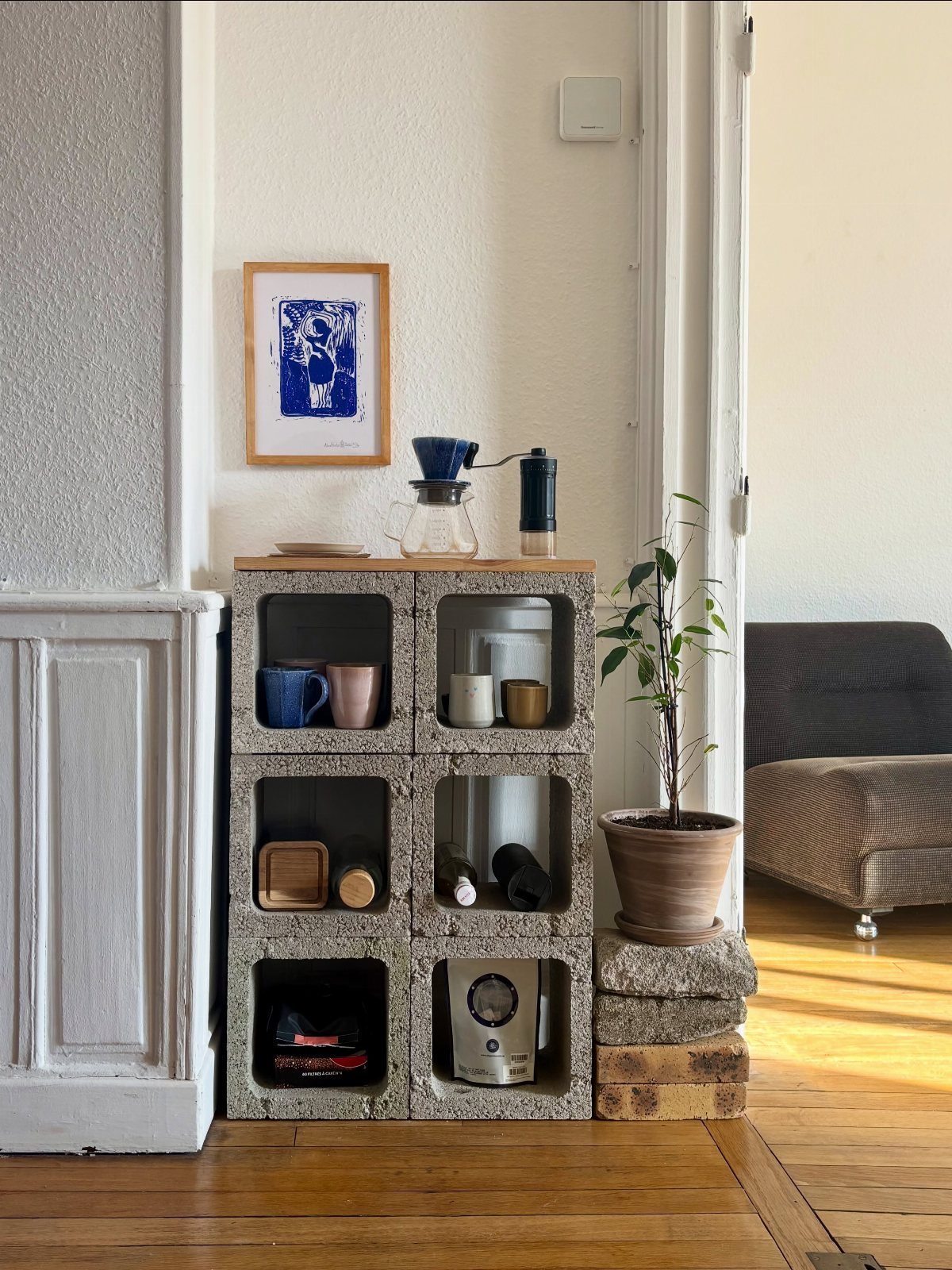 Concrete cinder block shelving unit acting as a coffee station with mugs and brewing equipment.