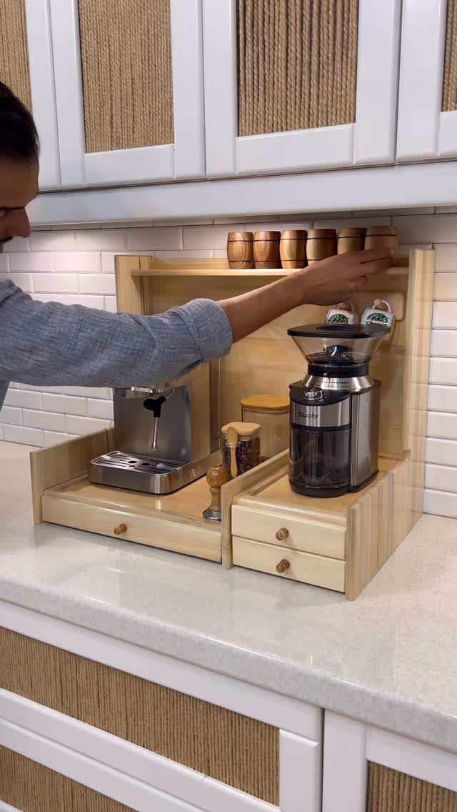 A person reaching for wooden canisters on a tiered wooden coffee organizer on a kitchen counter.
