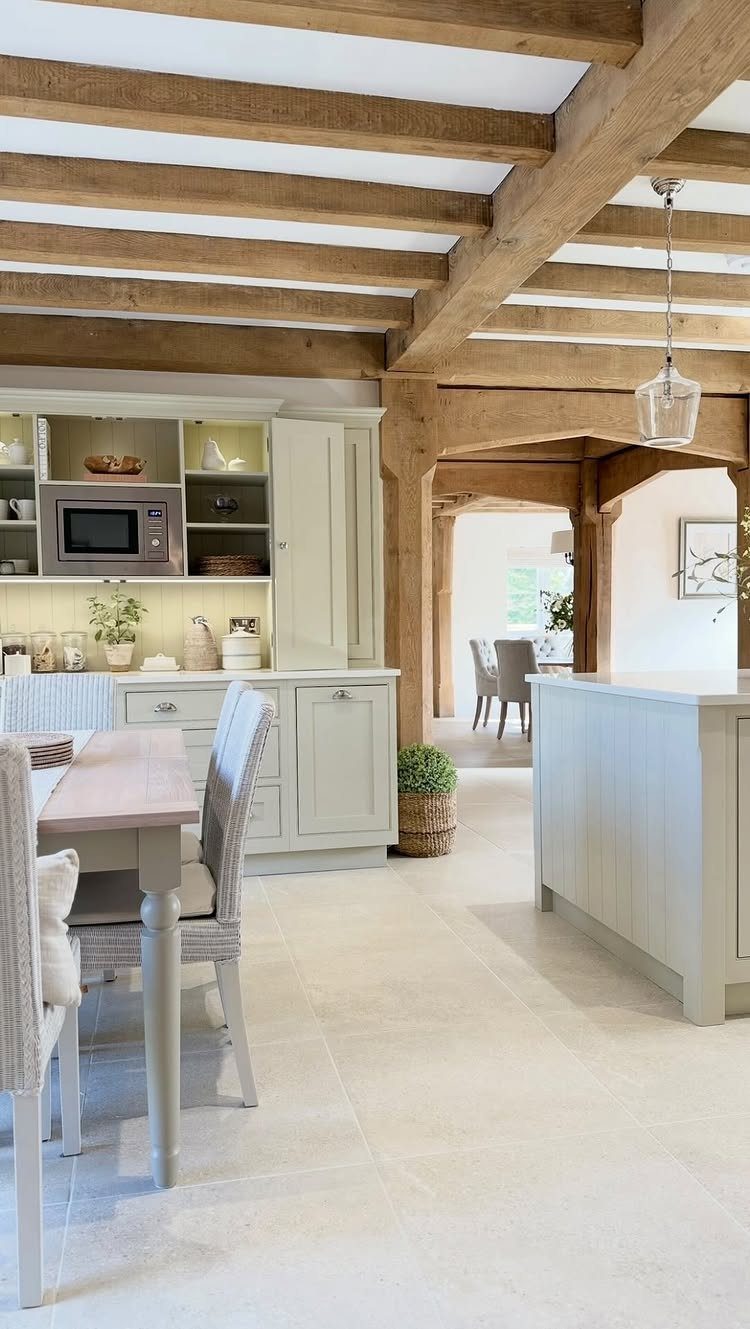 Large light wood exposed beams running across a bright, modern country style kitchen ceiling.