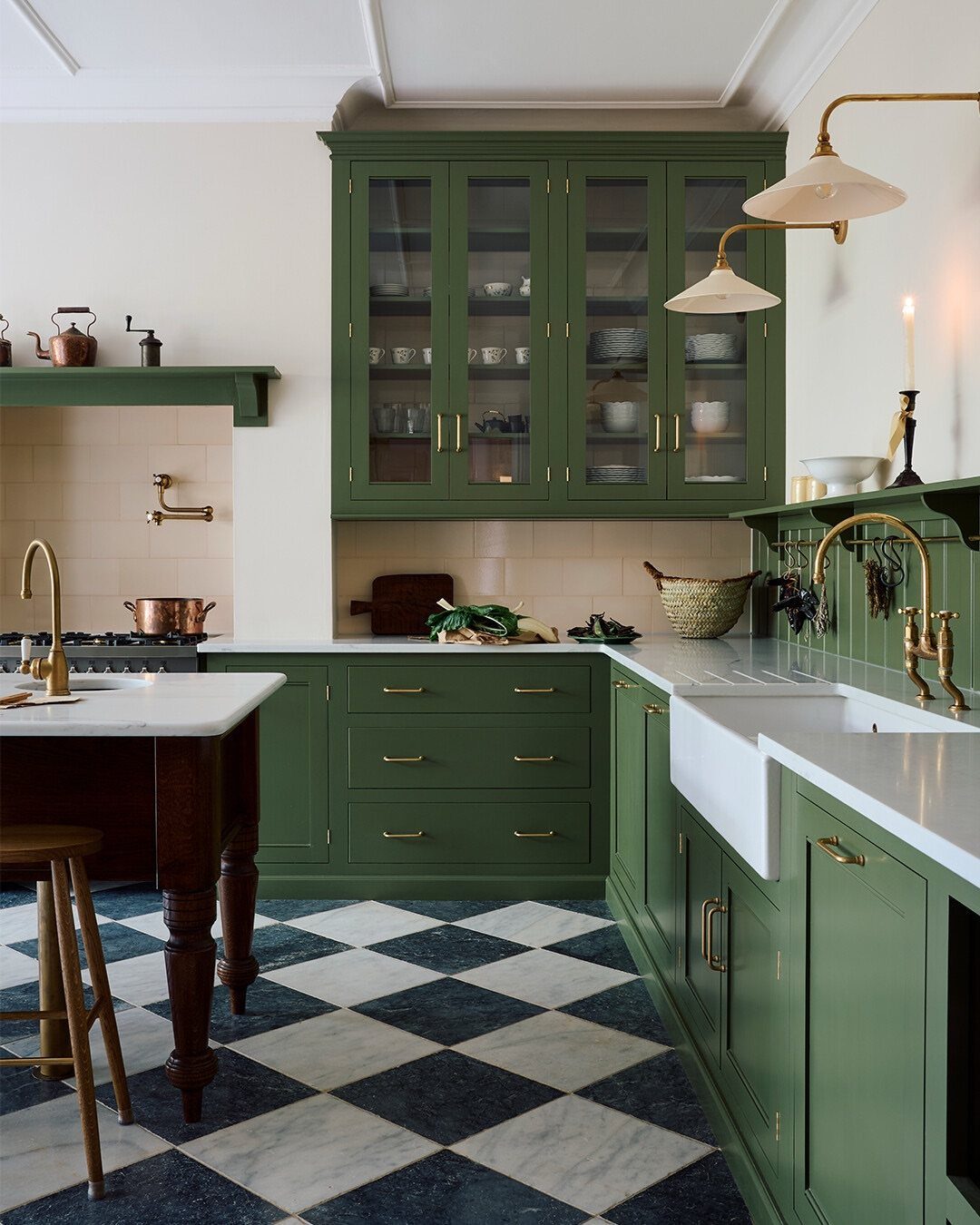Green shaker-style kitchen cabinets with a white farmhouse sink and checkerboard flooring.