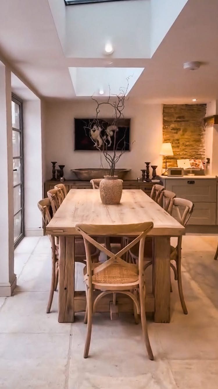 A large wooden dining table surrounded by wooden cross-back chairs in a neutral room.