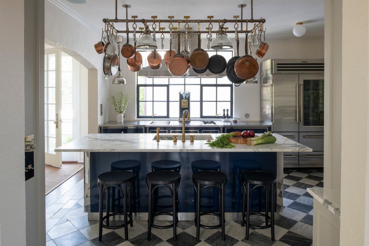 A large metal pot rack filled with copper and silver pans hanging over a kitchen island.