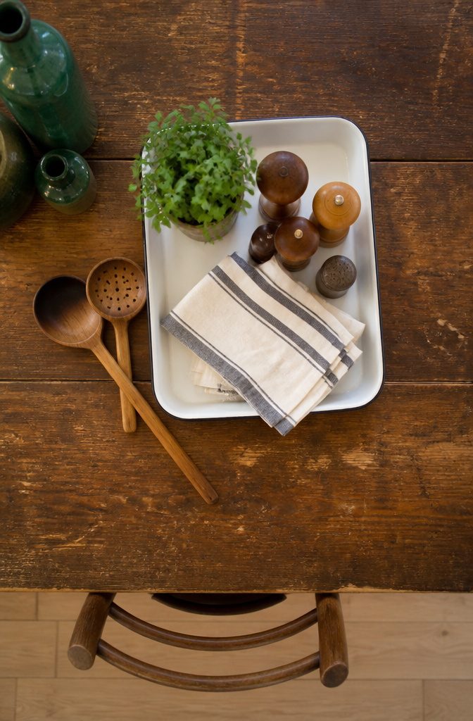 A compact enamel tray with napkins and shakers on a table.
