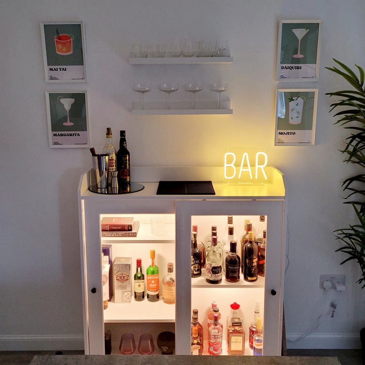 White wooden bar cabinet with illuminated shelves, glassware, and various liquor bottles inside.