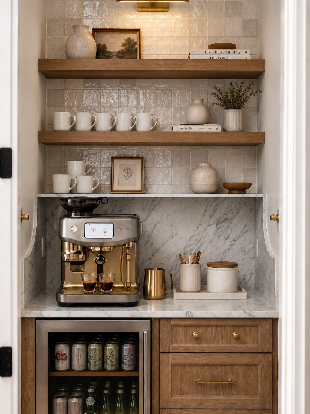 A built-in coffee station with marble counters, wooden shelves, an espresso machine, and a small beverage fridge.