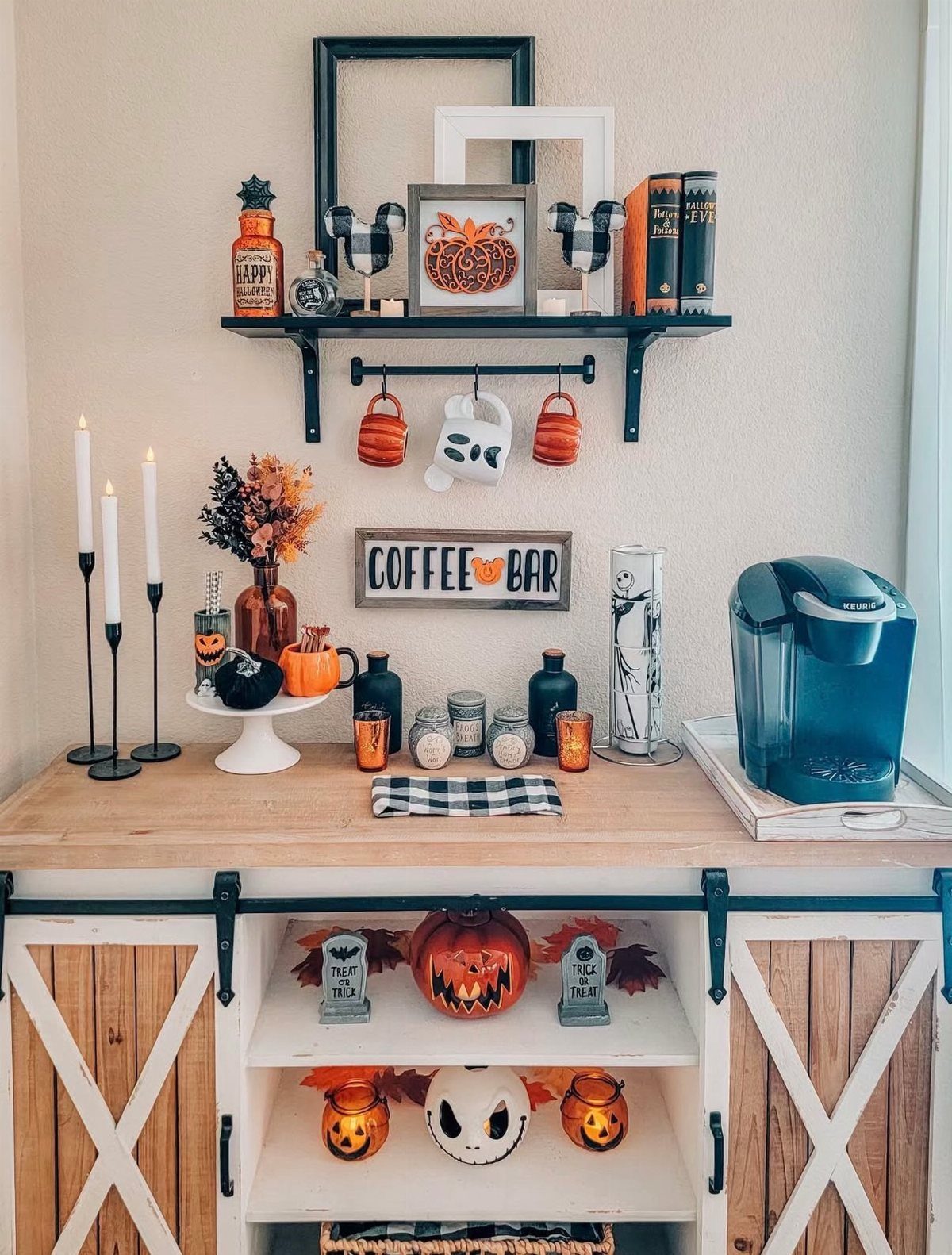 Halloween themed coffee bar cabinet with pumpkins, mugs, and decorative seasonal items on a wooden countertop.