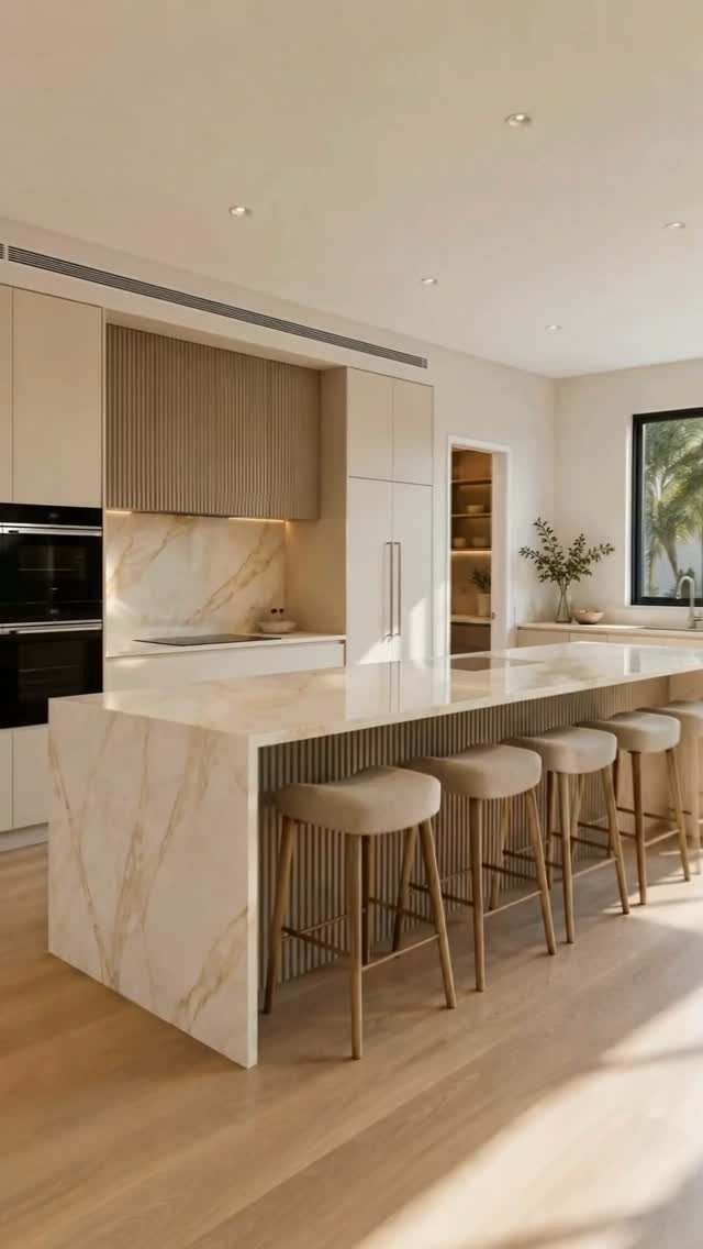 Large marble waterfall kitchen island with four wooden bar stools in a bright modern kitchen.