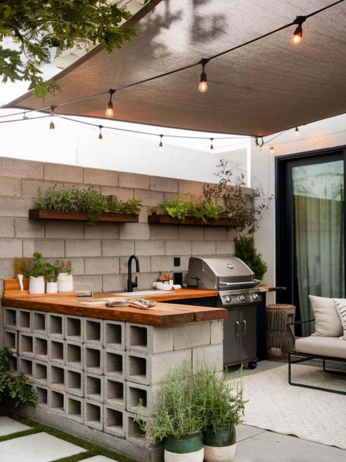 An outdoor kitchen with a cinder block base, wooden countertops, and a stainless steel grill.