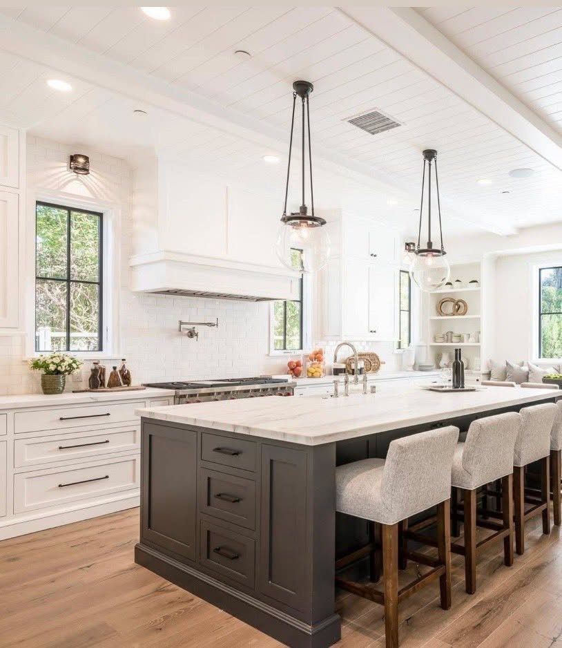 Dark grey painted kitchen island with white marble countertop and grey upholstered bar stools.