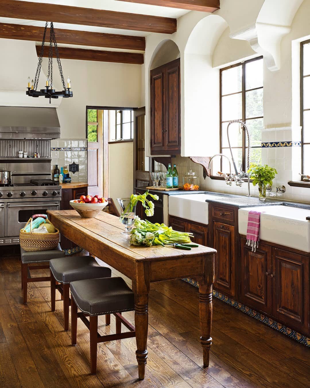 A long wooden vintage table used as a kitchen island with fresh vegetables on top.