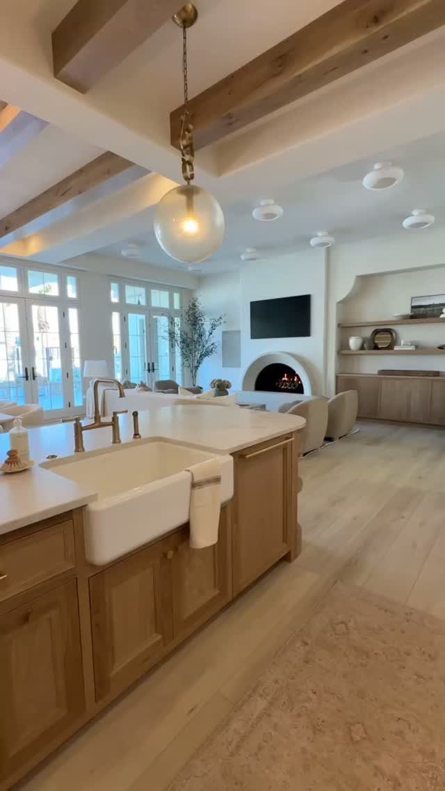 Light wood kitchen island with a white farmhouse sink and warm white countertops.