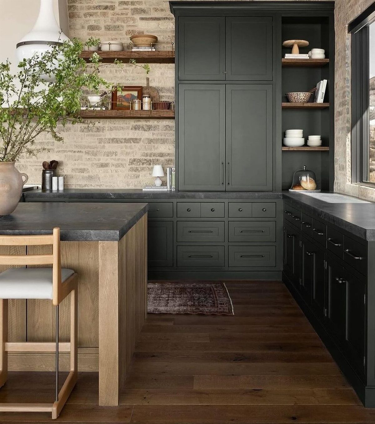 Green Kitchen Cabinets: 12 Ideas for Every Shade 2 Dark green kitchen cabinets with black countertops and wooden shelves against a brick wall.