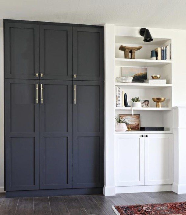 Dark grey built-in cabinets with gold hardware next to white shelving units.