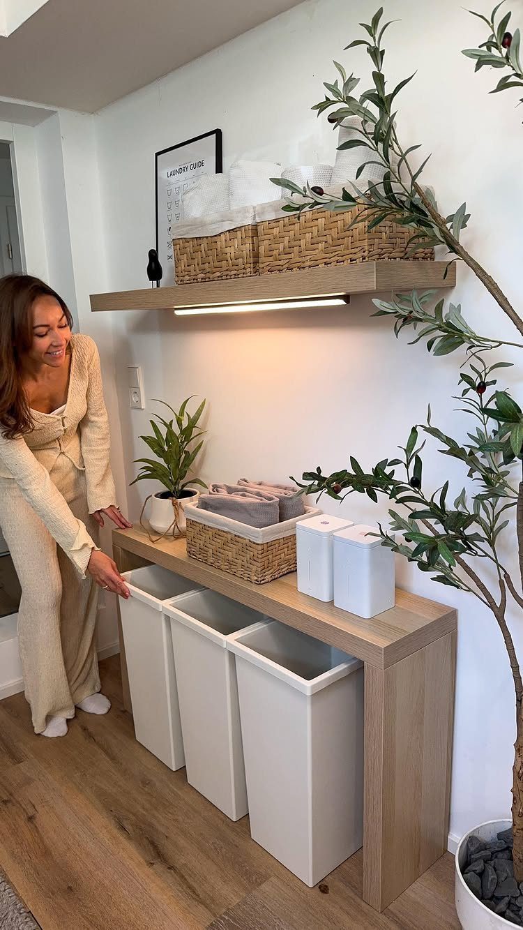 A woman reaches toward white storage bins tucked under a light wood console table.