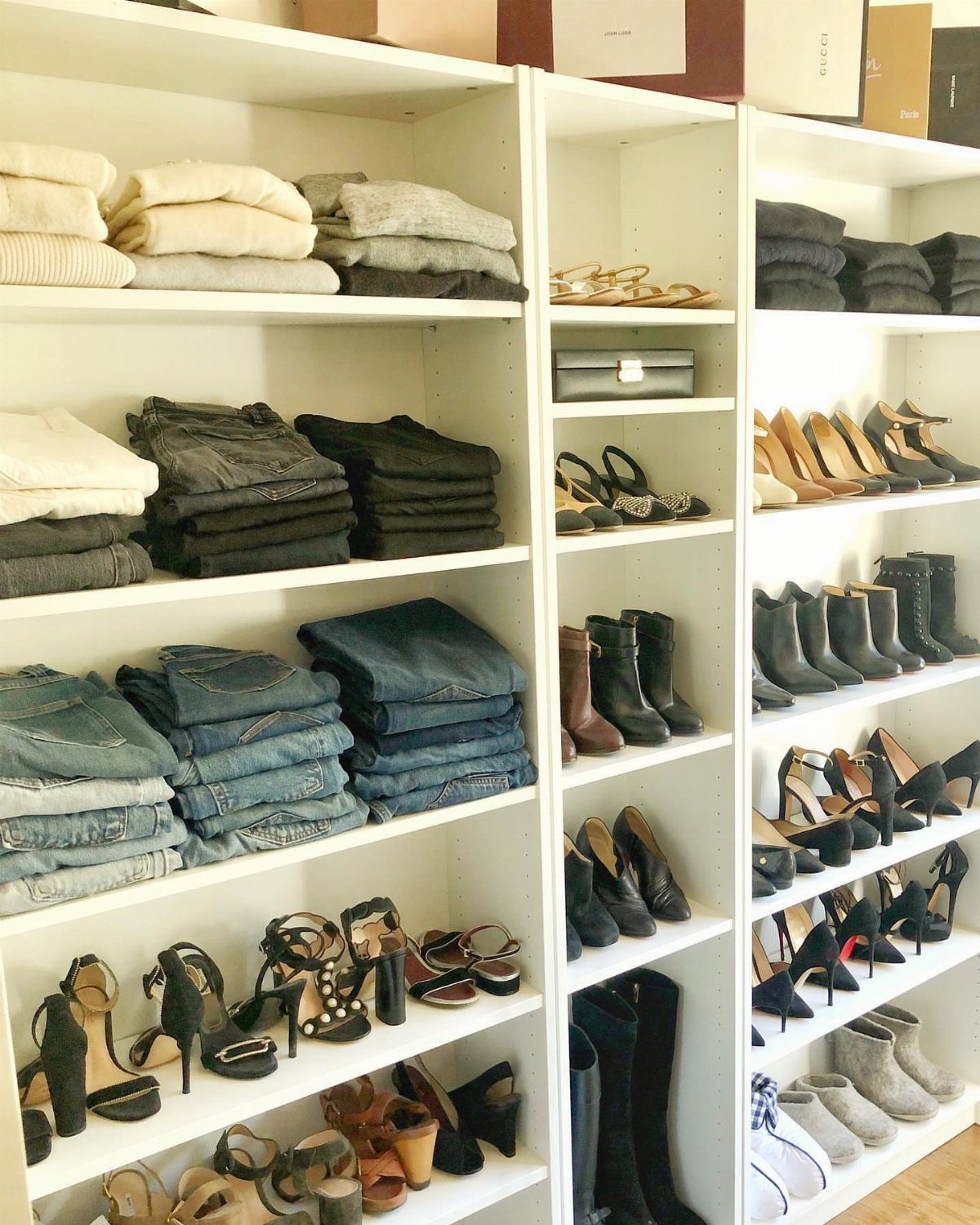 White shelving units filled with folded clothing and rows of organized shoes.