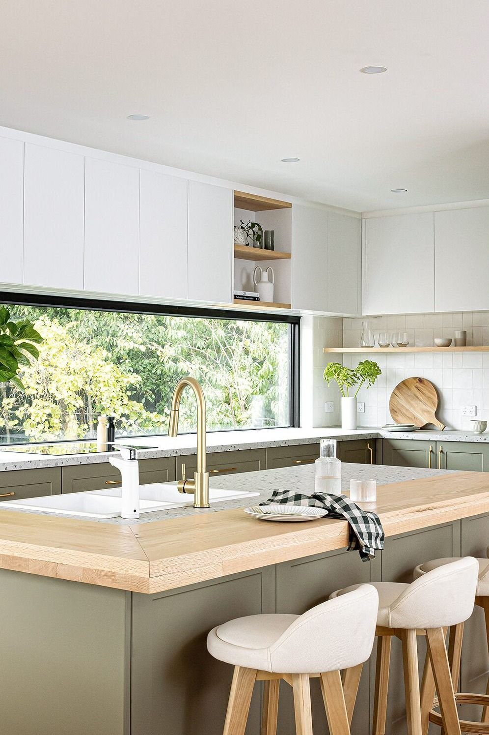 Olive green kitchen cabinets paired with light wood countertops and matching wooden bar stools.