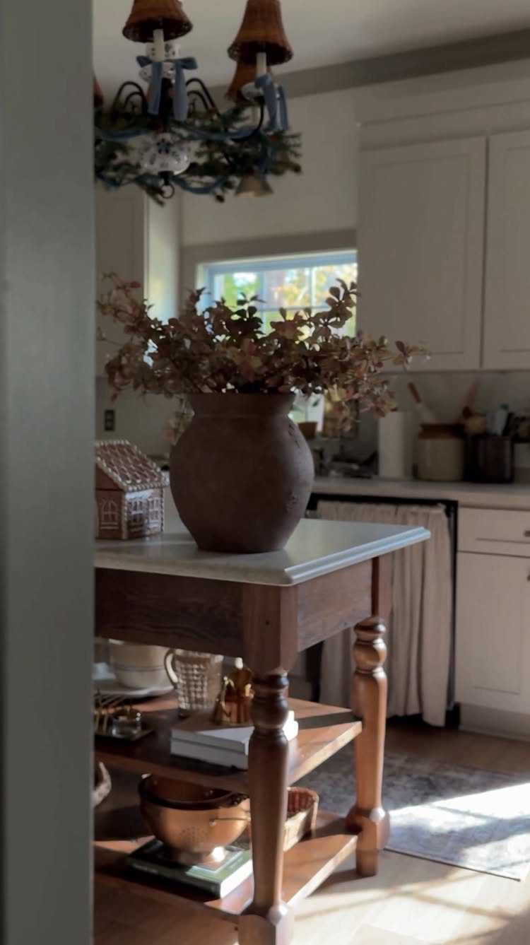 Wooden kitchen island with marble top and open storage shelves holding various kitchenware items.