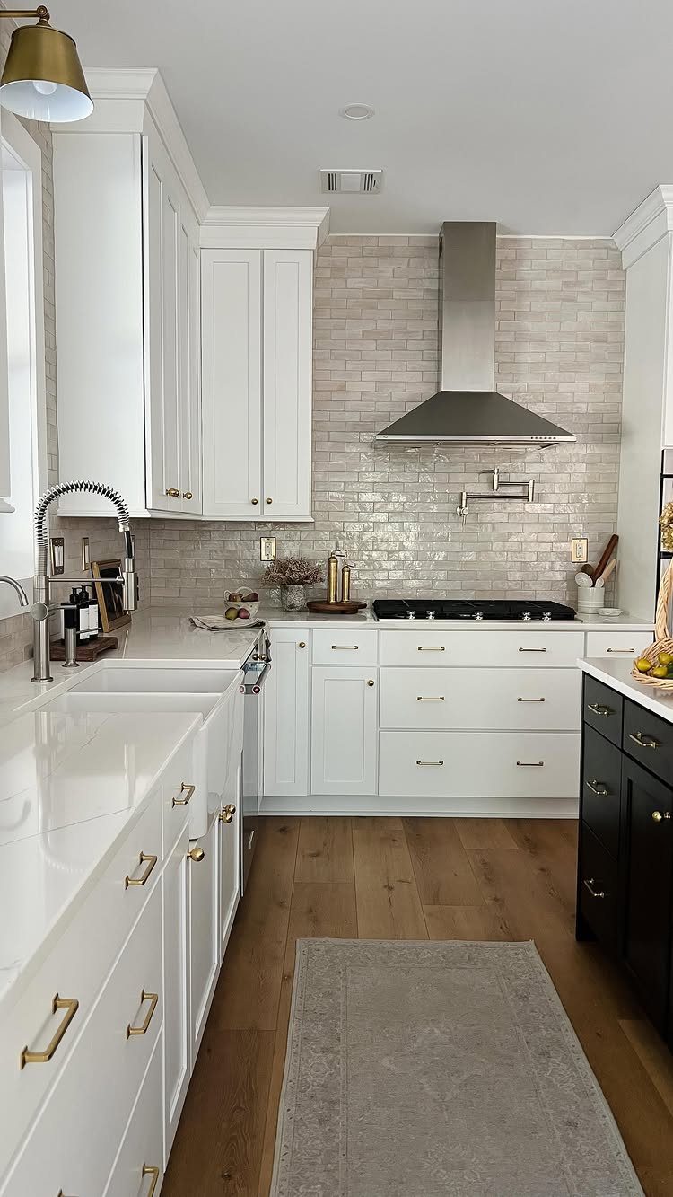 White kitchen cabinets with a light-colored textured tile backsplash and stainless steel range hood.