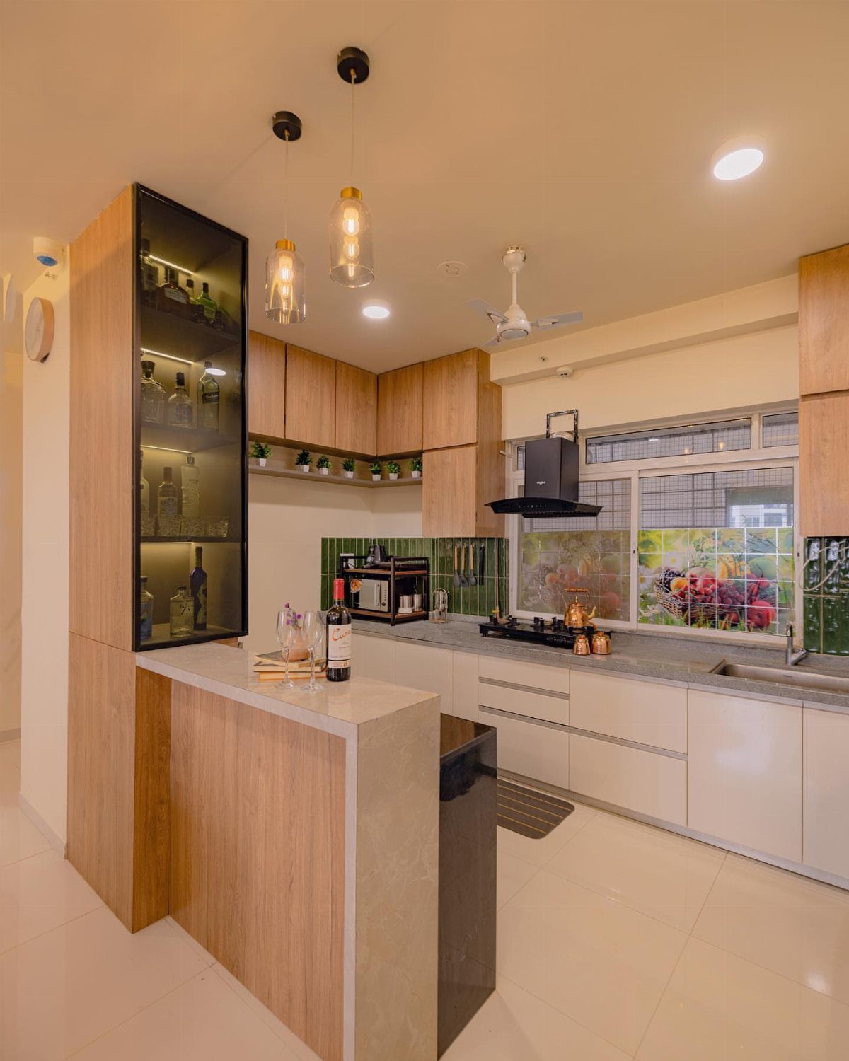 A modern kitchen with light wood cabinets and a small breakfast bar with pendant lights.