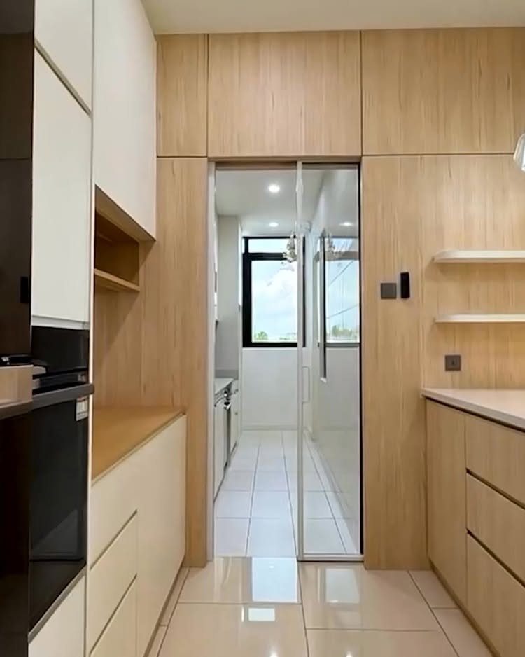 Sliding glass doors with black frames partition a modern kitchen from a bright utility room.