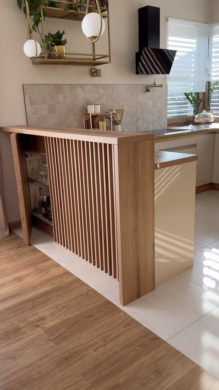 A kitchen island with a decorative vertical wooden slat partition facing a light wood floor.