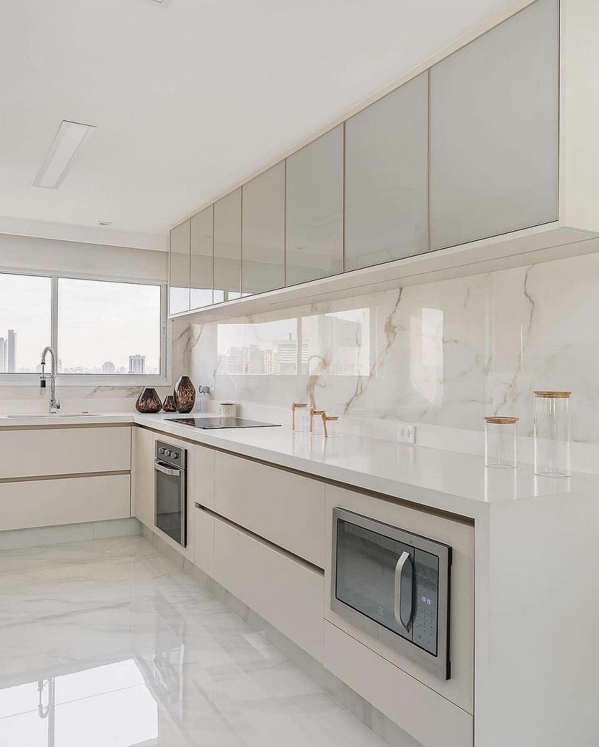 Modern kitchen with white cabinets, marble countertops, and a large marble-patterned backsplash.
