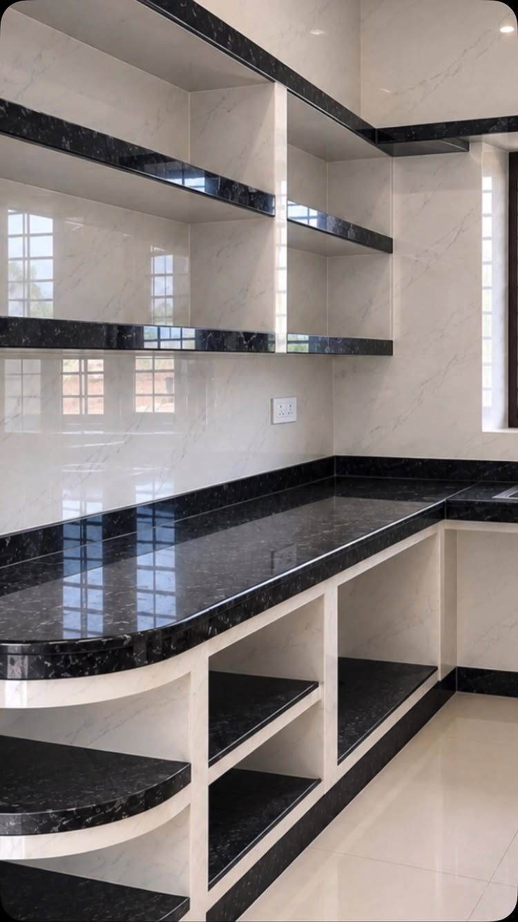 Black granite countertops and open shelving in a kitchen with white marble tiled walls.