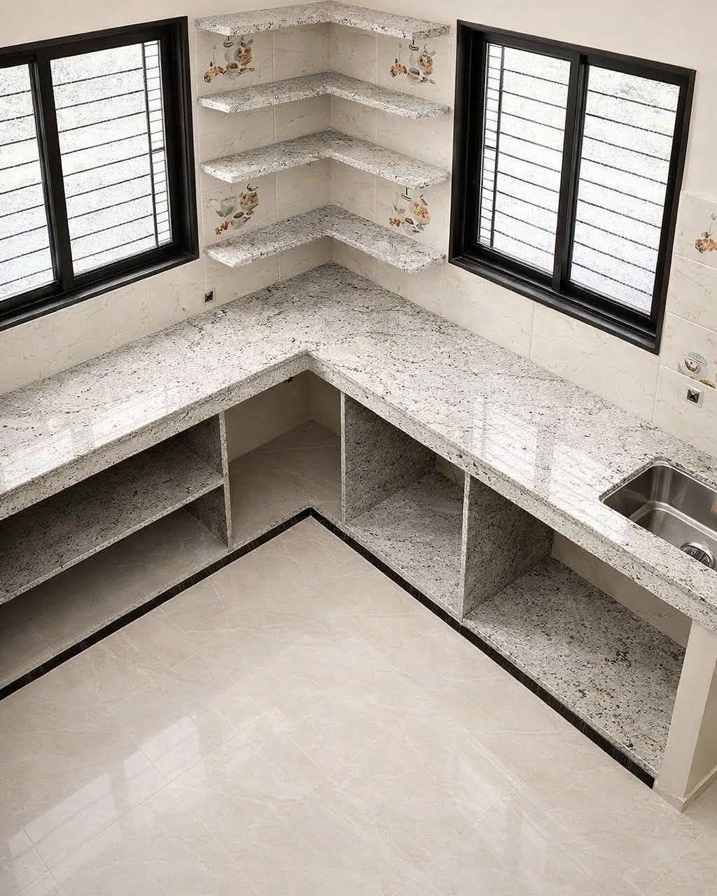 Granite countertops and matching corner floating shelves installed in a bright kitchen corner between two windows.