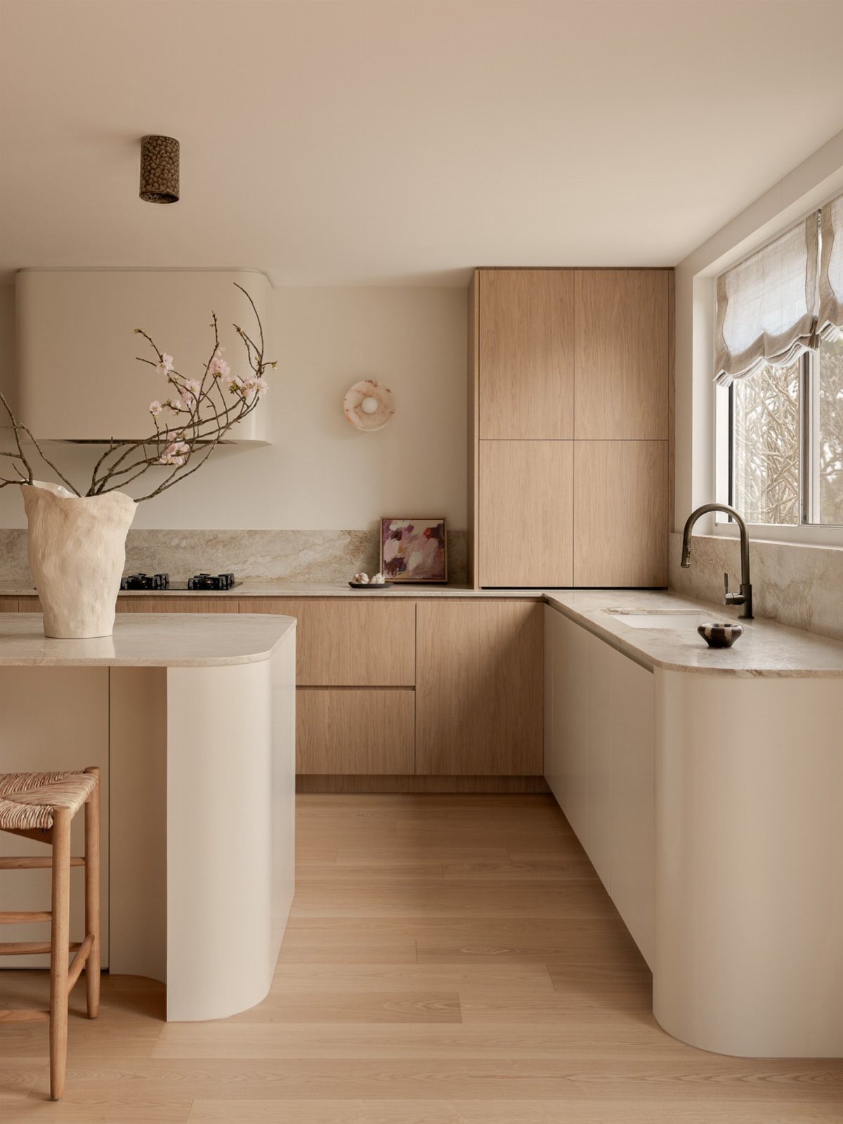 Minimalist kitchen with light wood cabinets, cream curved counters, and a matching kitchen island.