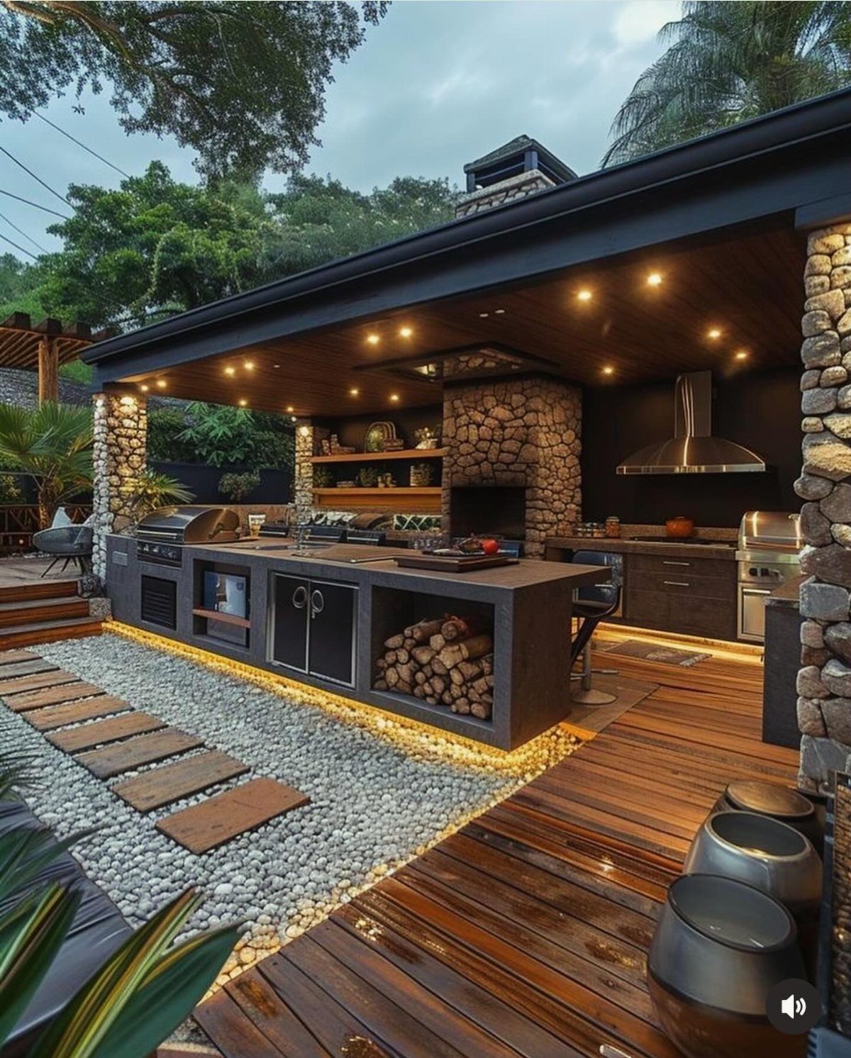 A luxury outdoor kitchen with stone accents, built-in grill, and warm lighting on a wooden deck.