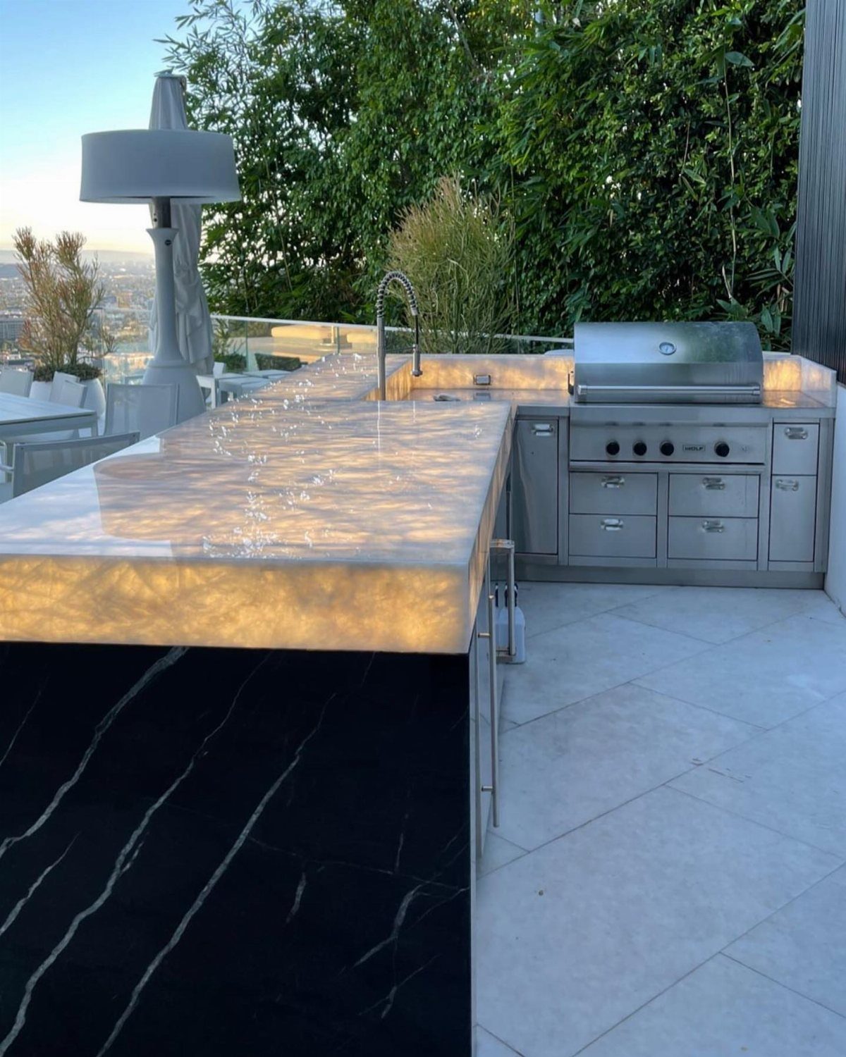 Polished light stone countertop with subtle veining in an outdoor kitchen with a stainless steel grill.