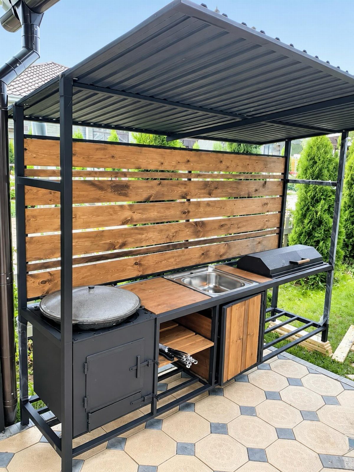 A black metal outdoor grilling station with a sink, wooden countertop, and built-in cabinets.