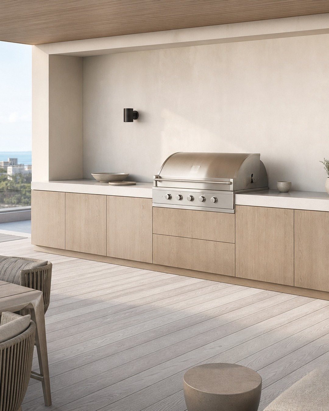 A large stainless steel gas grill built into light wood outdoor kitchen cabinetry.