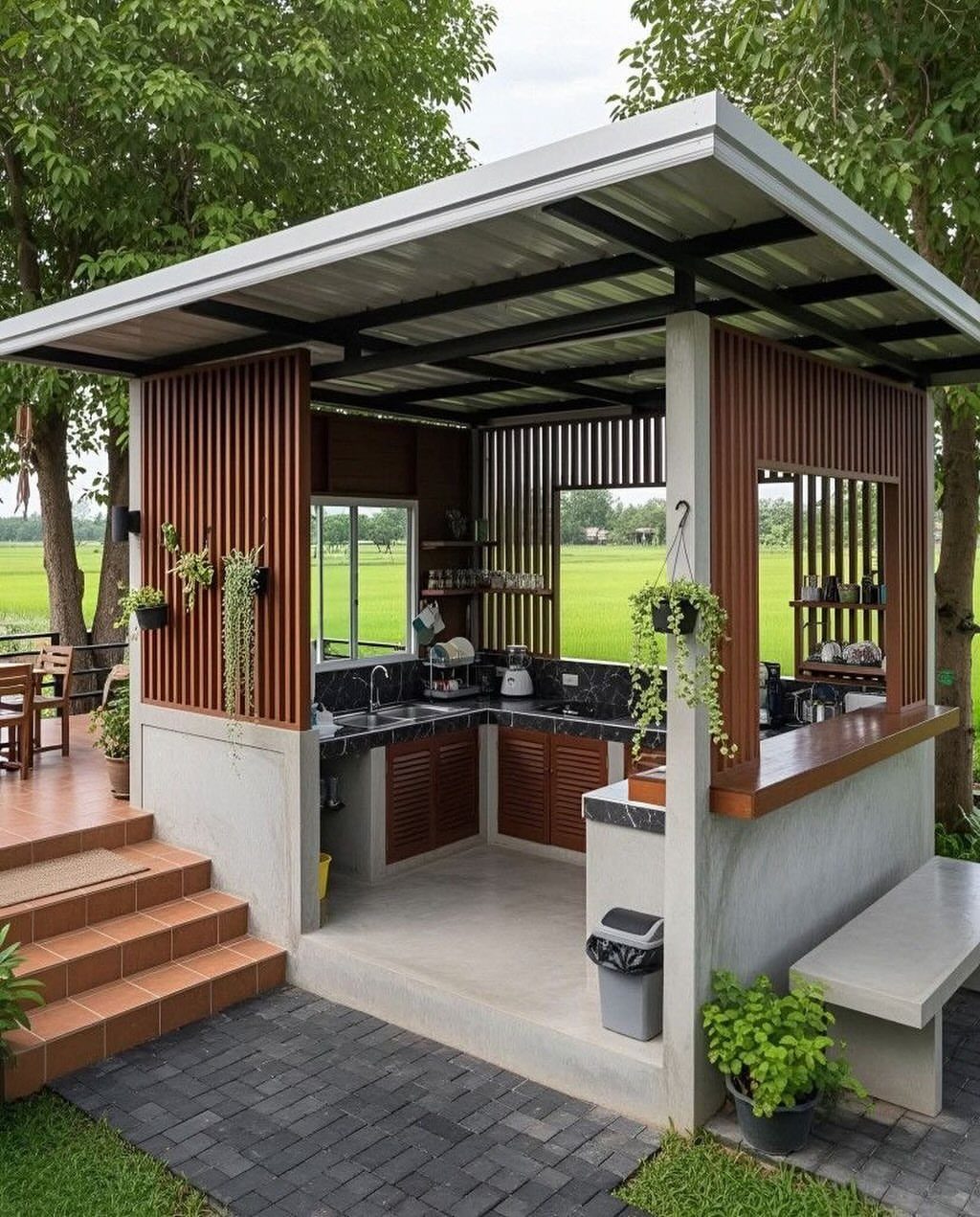 An L-shaped outdoor kitchen with dark countertops and wooden cabinets under a sheltered roof.