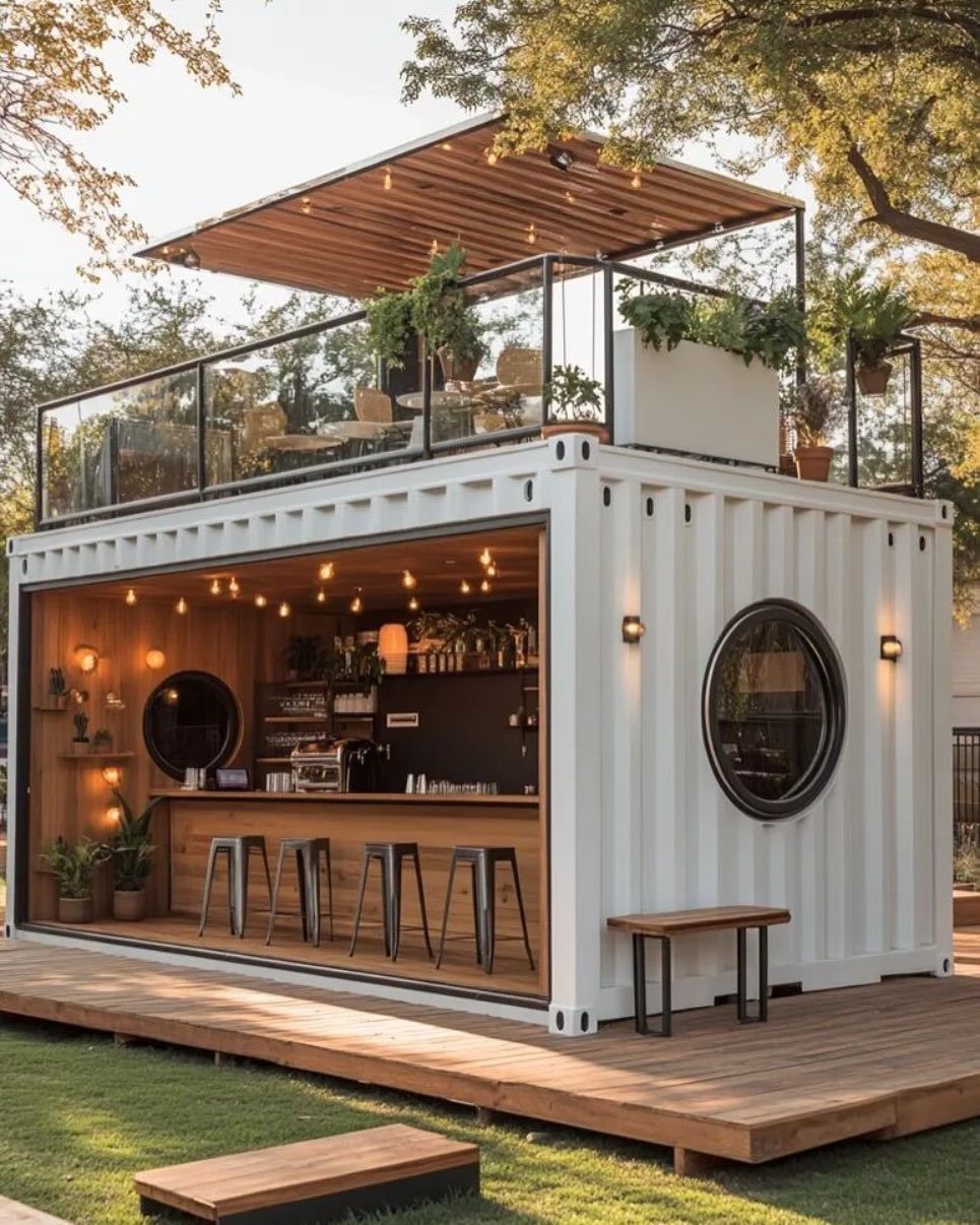 A white shipping container converted into a modern outdoor bar with a rooftop terrace and wooden decking.