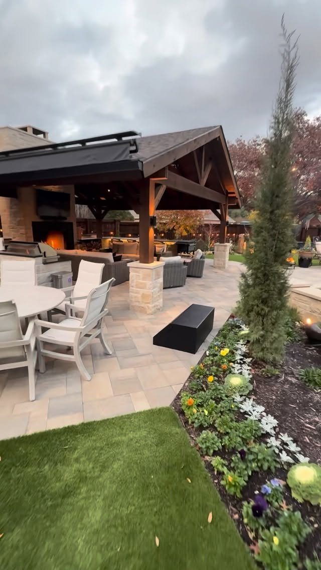 A covered outdoor kitchen and patio area with stone accents and comfortable seating.