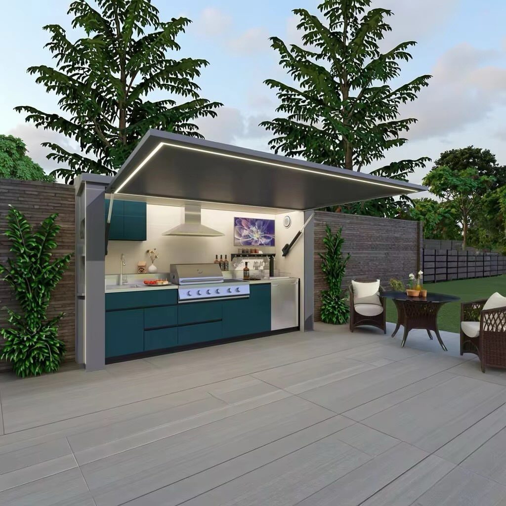 A modern teal outdoor kitchen with a stainless steel grill under a lit canopy on a grey deck.