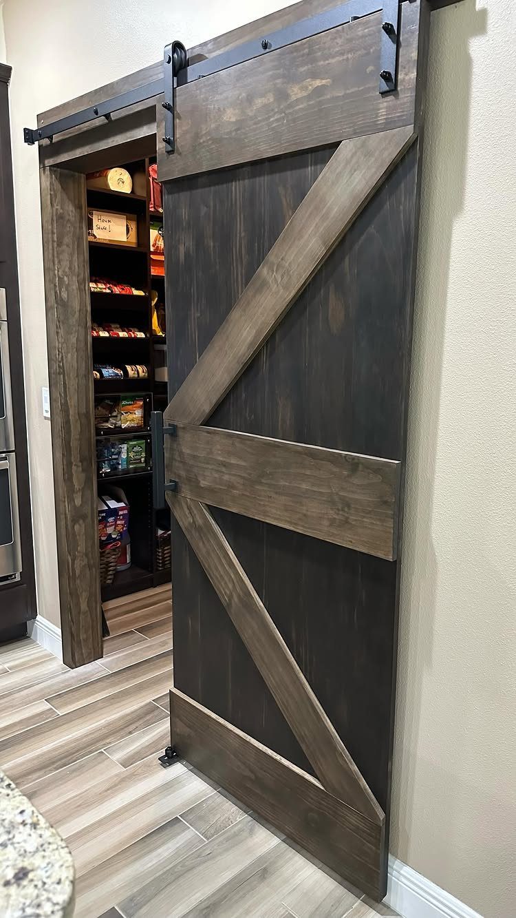 A dark wood barn door with a K-pattern sliding on a black metal track.
