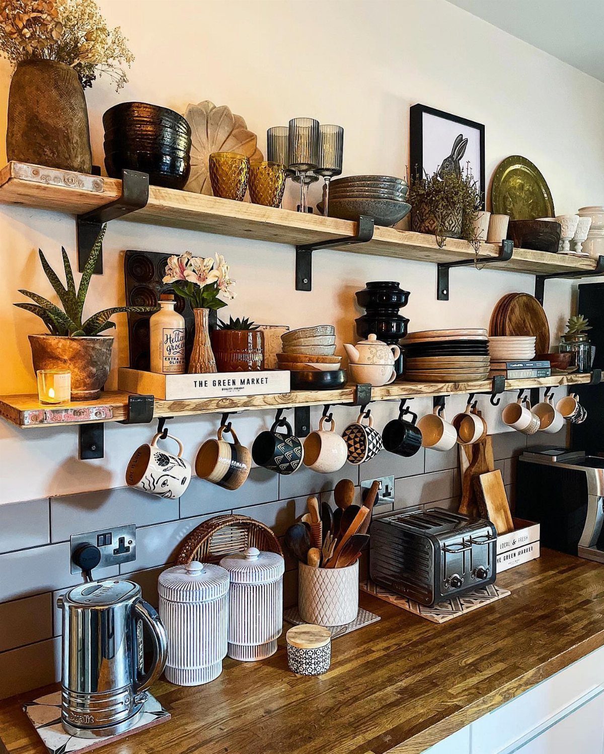Wooden open shelves holding various kitchenware and decor items against a white wall.