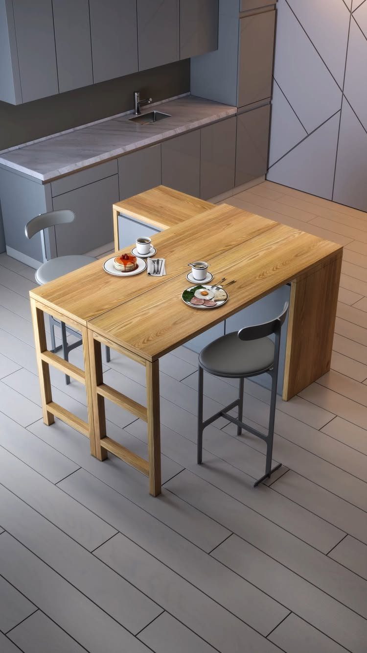 Wooden dining table attached to a kitchen island with grey chairs and breakfast settings.