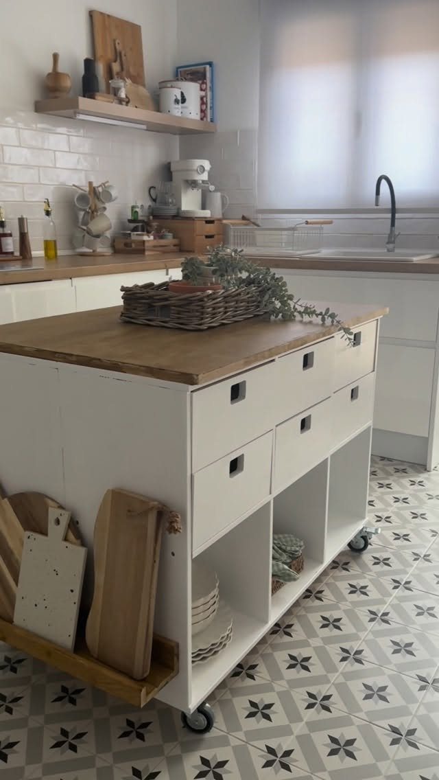 A white mobile kitchen island with wooden top and open storage shelves on wheels.